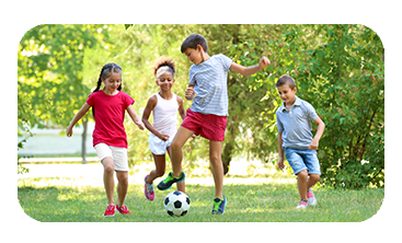 Four kids playing soccer outside.